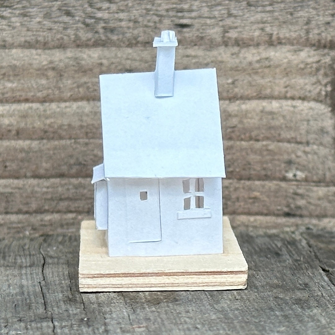 white paper gable fronted house with double chimney on plywood base 