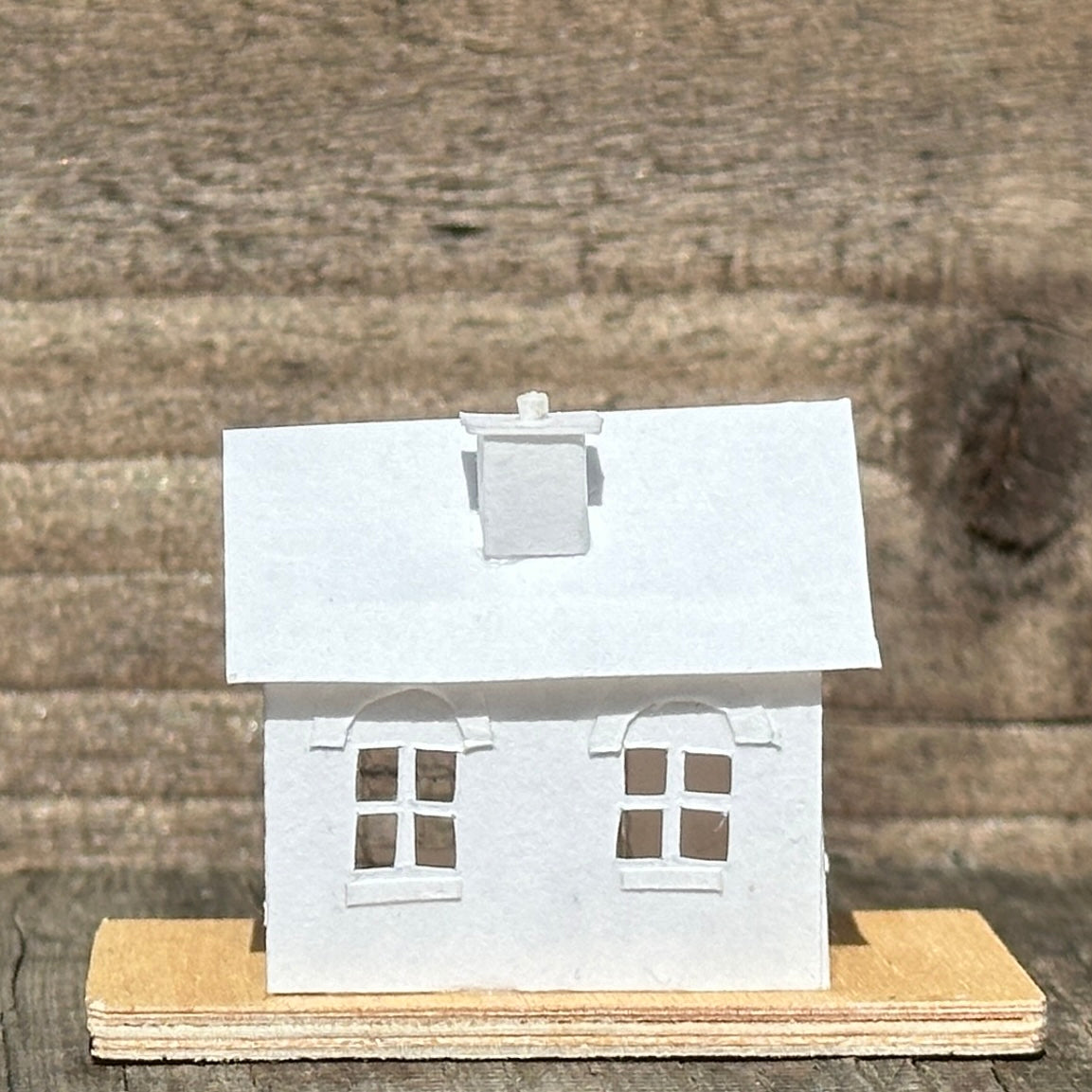 white paper house with arched windows on plywood base