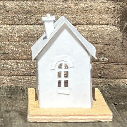 white paper house with arched windows on plywood base