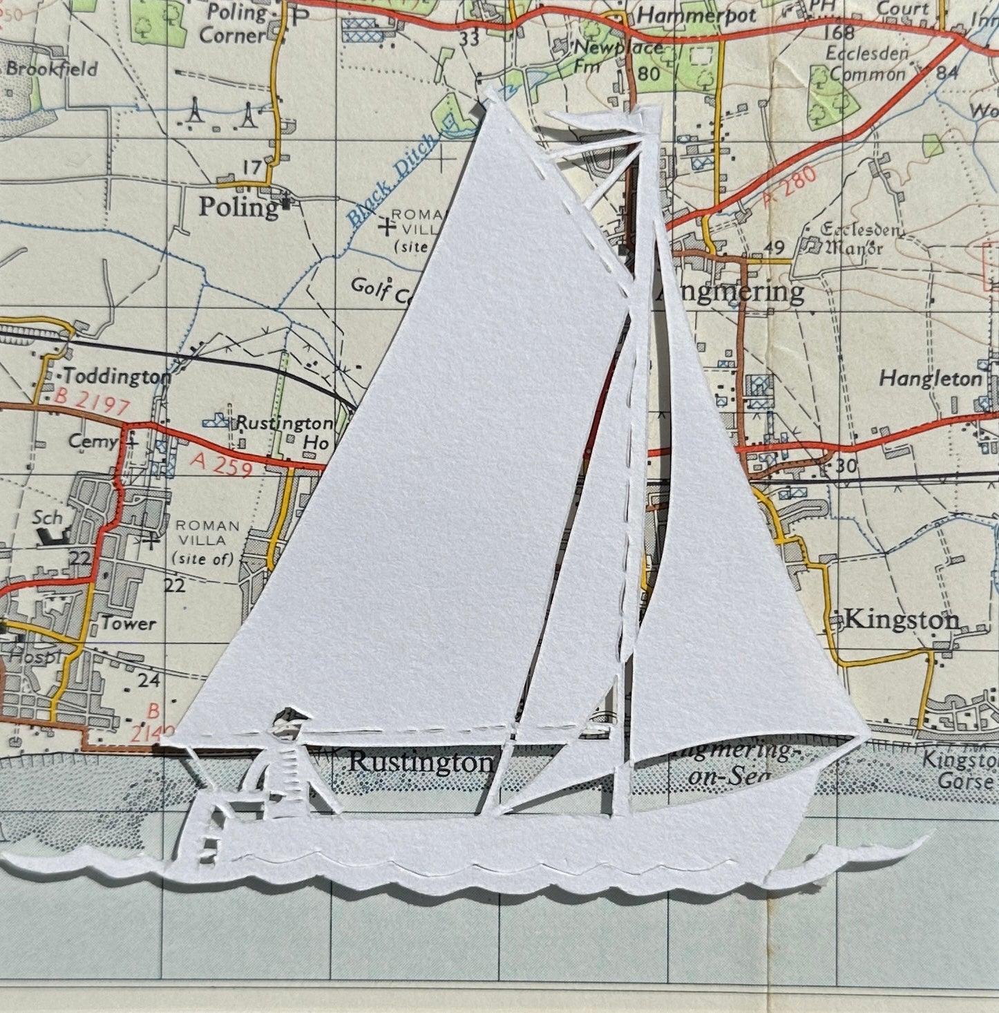 Papercut of sailing dinghy over an OS map extract
